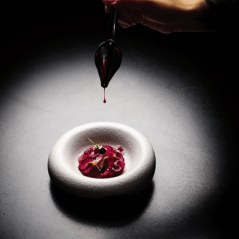 Plat raffiné dressé sur assiette noire au design déstructuré.