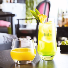 Gobelet Lima 35cl avec jus d'orange, posé à côté d’un verre cocktail