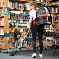 Opérateur nettoyant une bibliothèque avec aspirateur dorsal sans fil