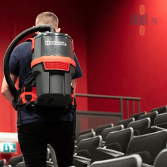 Utilisateur aspirant des gradins de salle avec aspirateur dorsal Numatic
