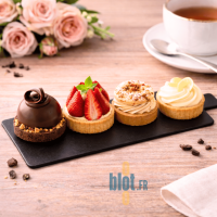 Mini pâtisseries assorties disposées sur support rectangle noir à languette