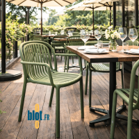 Fauteuil SERENA vert olive installé en terrasse de restaurant avec table extérieure